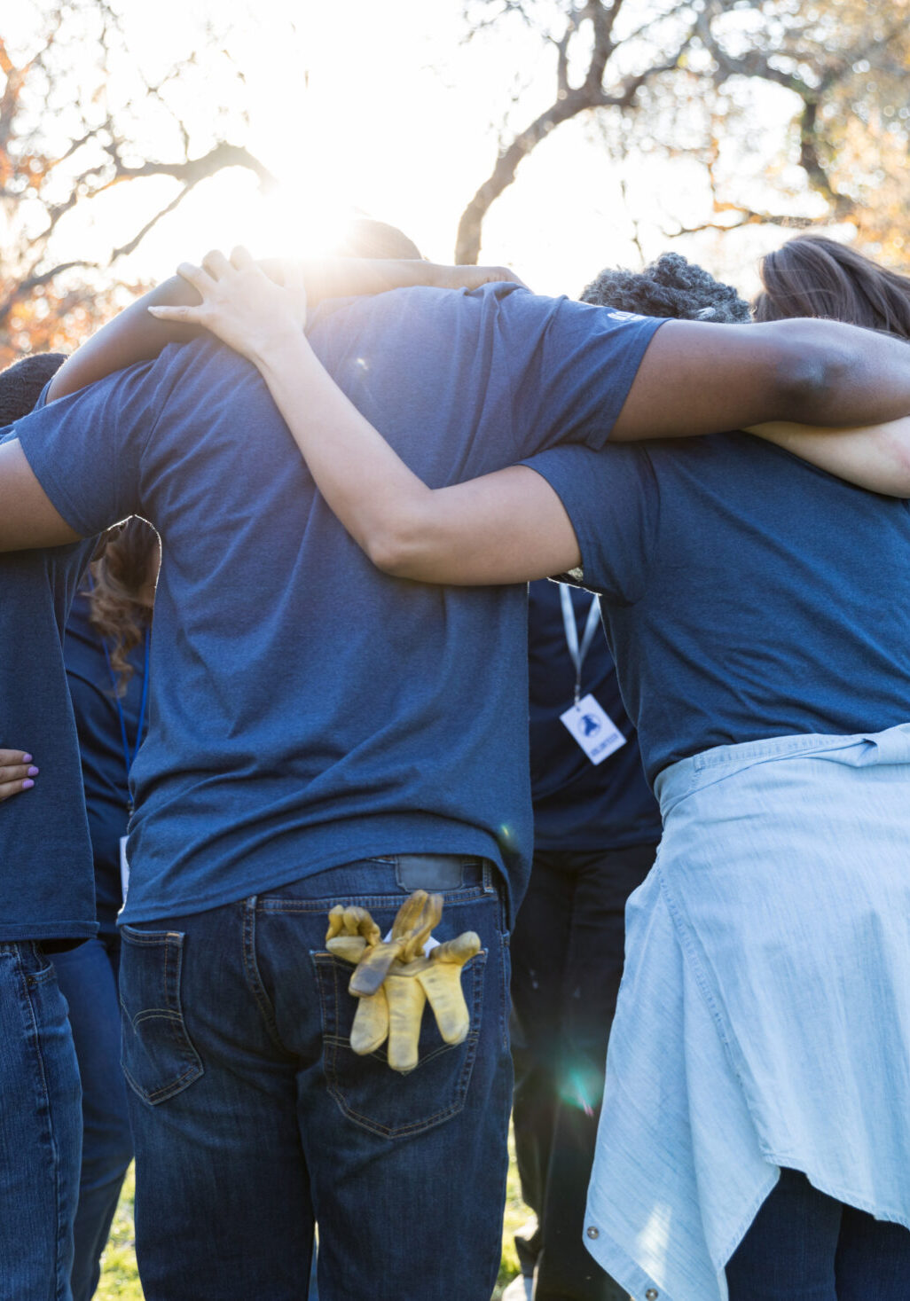 Unrecognizable group of volunteers huddle together after a successful community cleanup event.